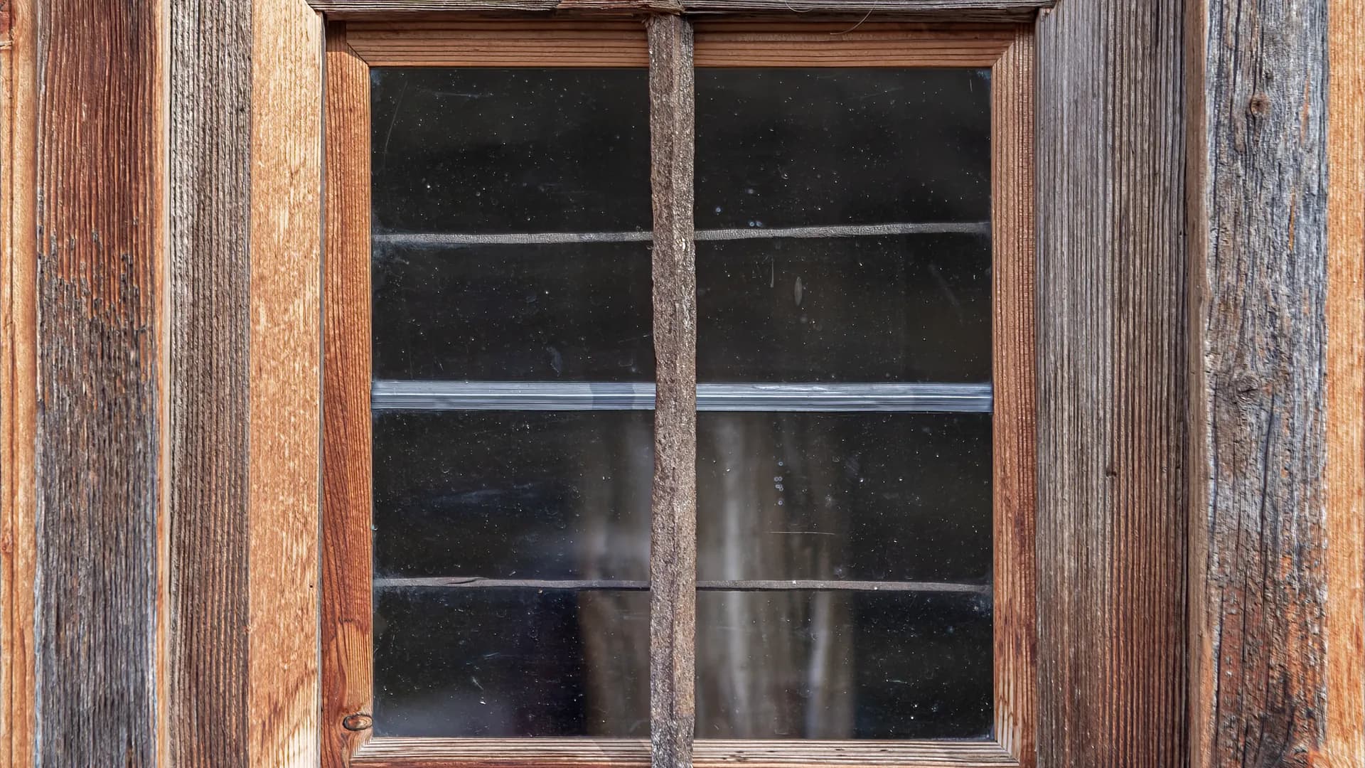 Ein verwitterter Holzfensterrahmen mit echter Holzmaserung.