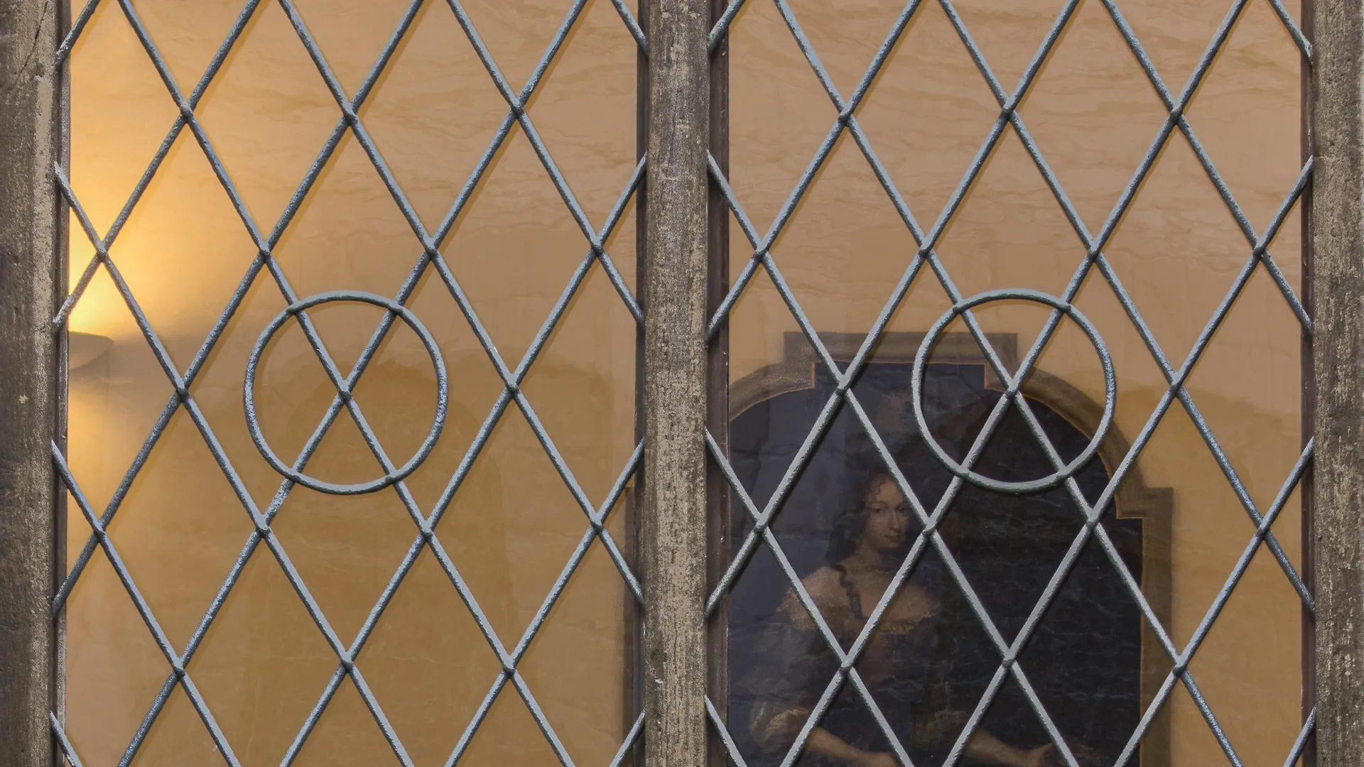 A leaded lattice window with many small panes in warm tungsten light.