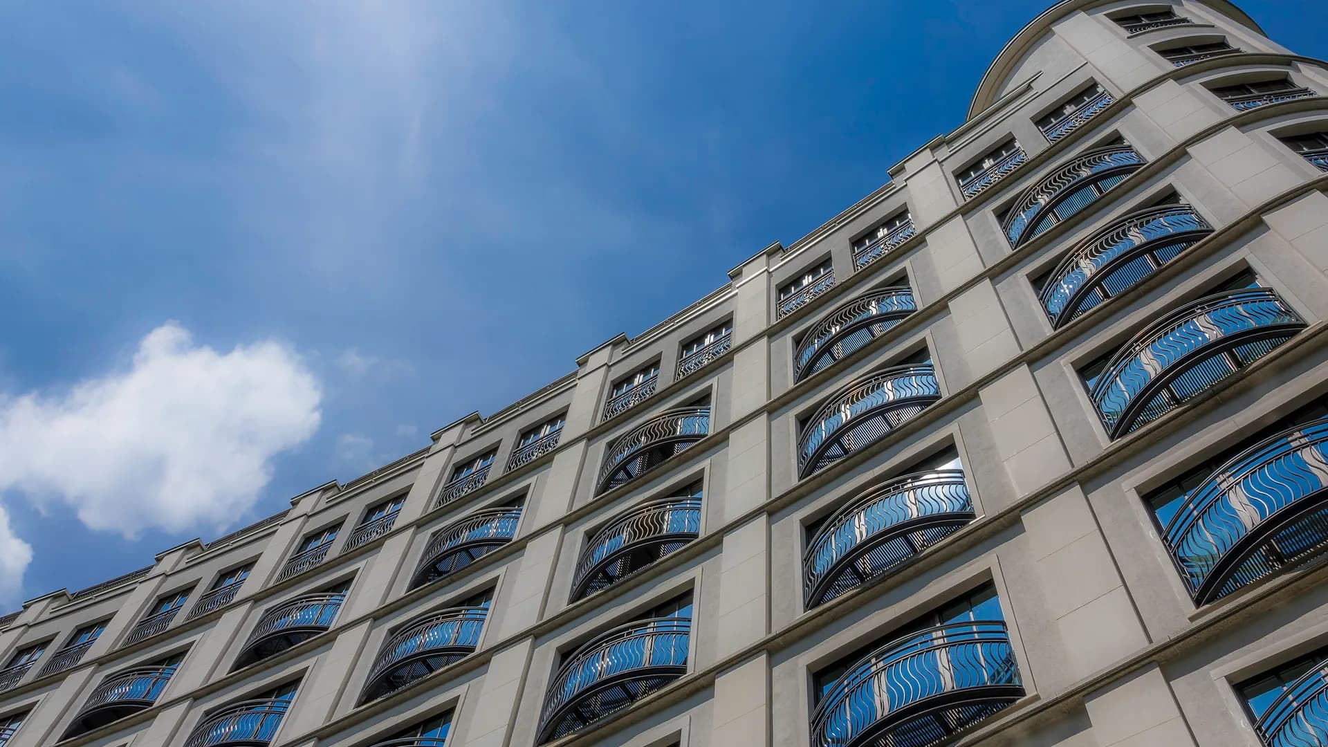 A residential facade with curved balcony railings under a blue sky.